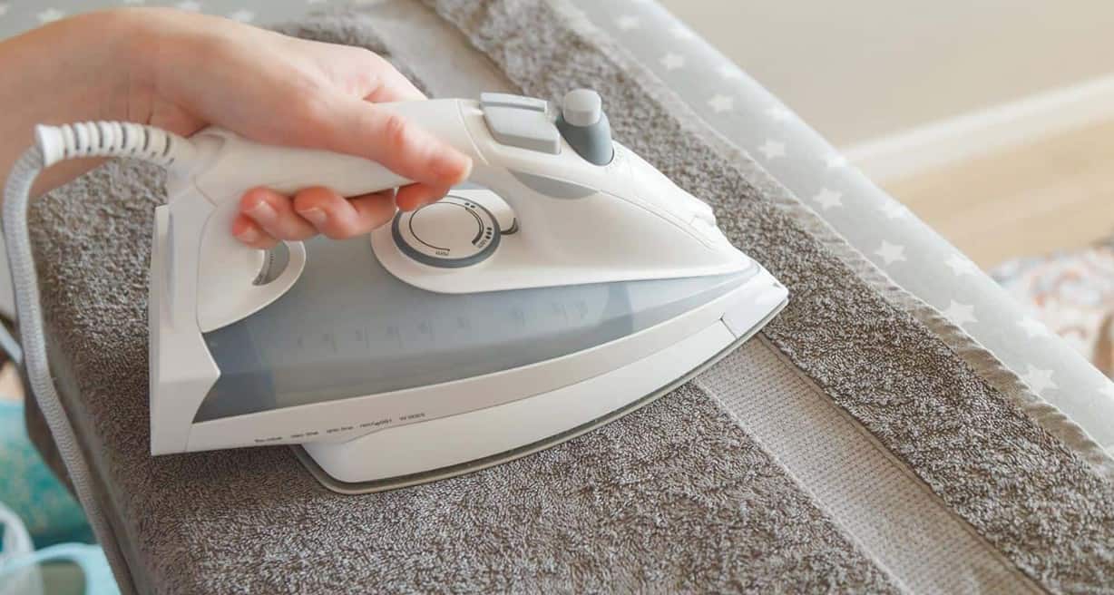 Lay your wet garment on the ironing board with a cloth on top of it
